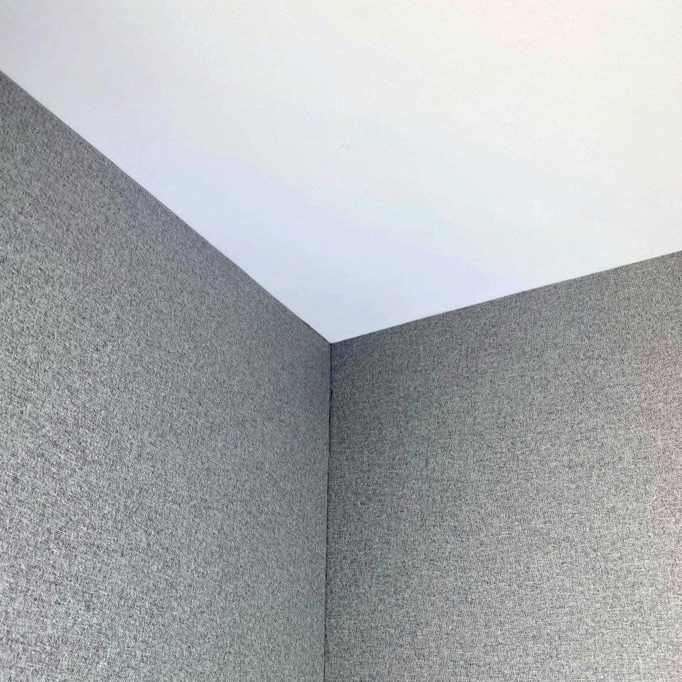 Grey textile wall installation in a room corner with a clean ceiling line