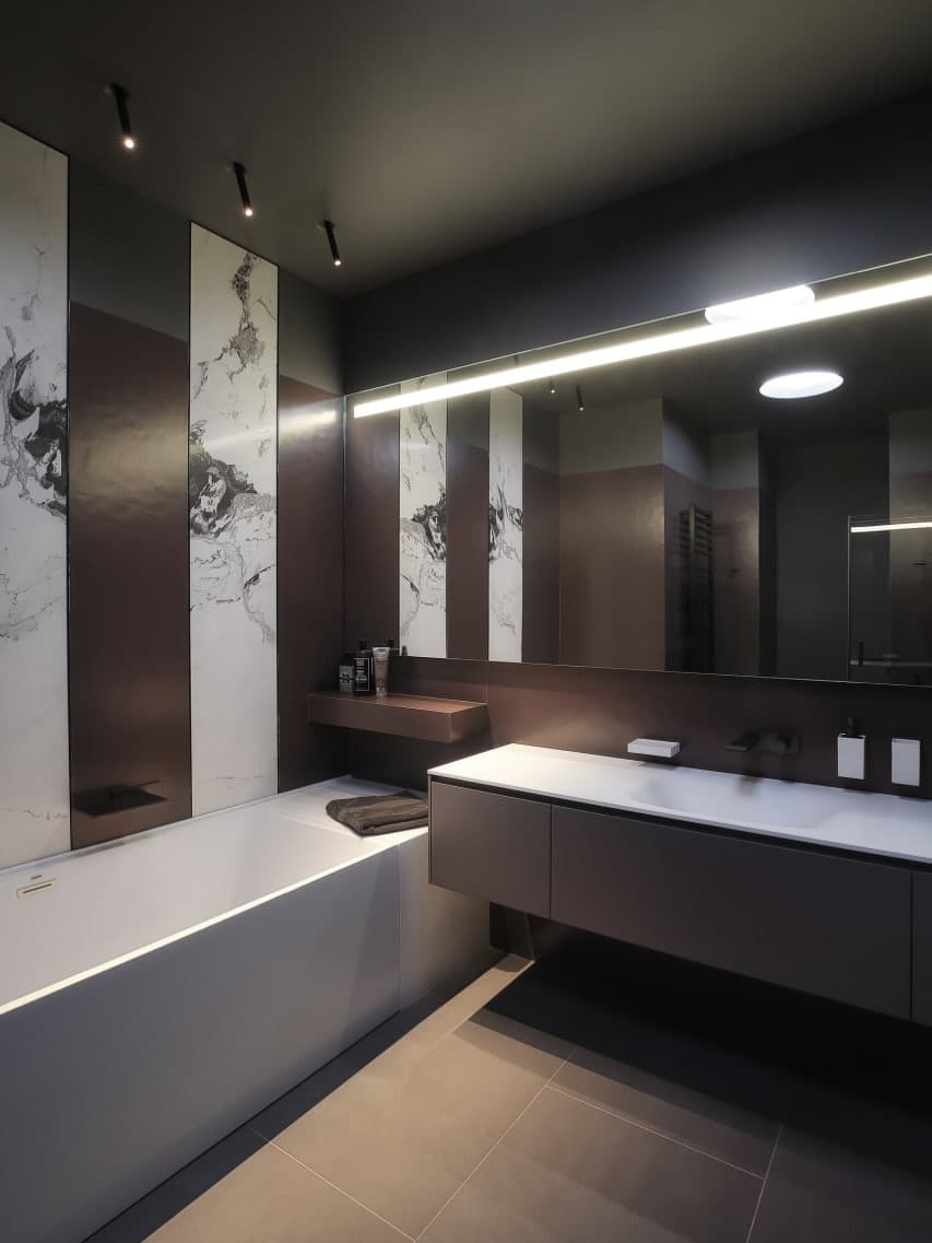 Baño reformado en Barcelona con azulejos de gran formato, insertos decorativos efecto mármol, mueble suspendido e iluminación integrada