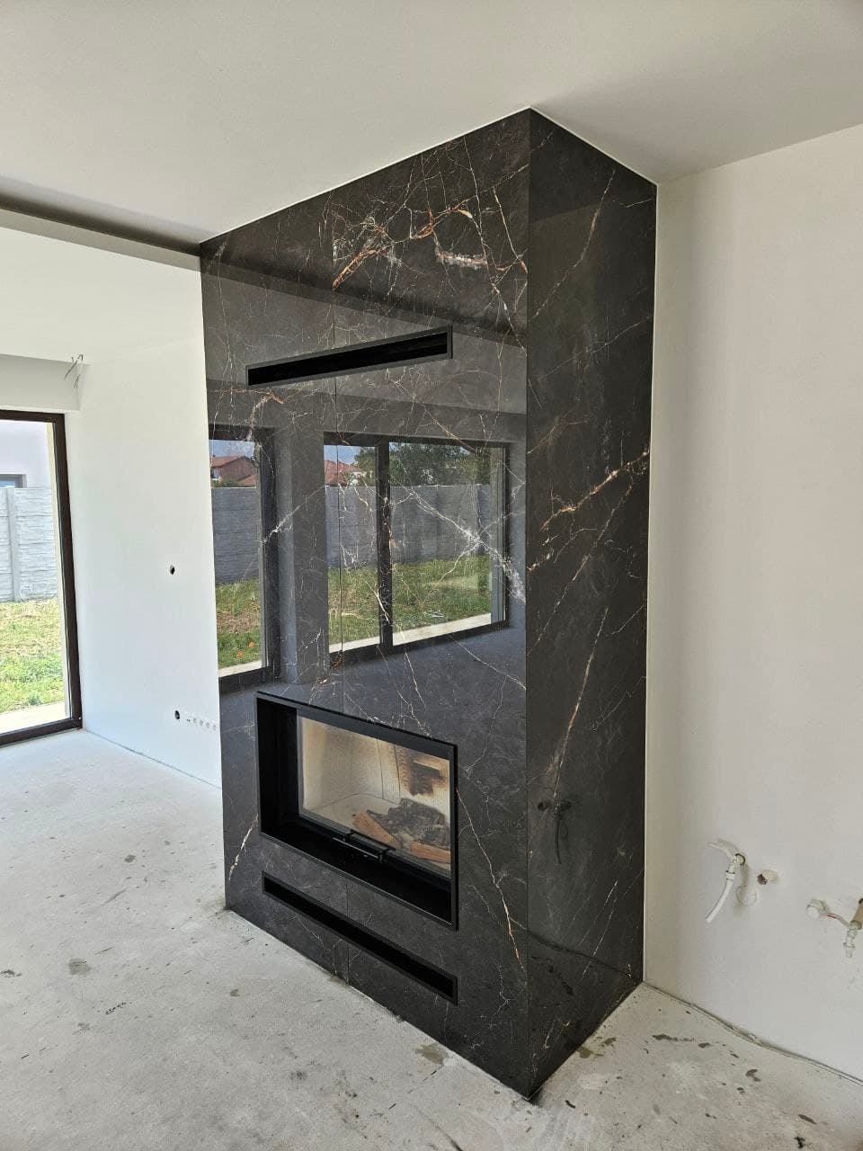 Fireplace wall with dark ceramic slabs and an architectural hearth