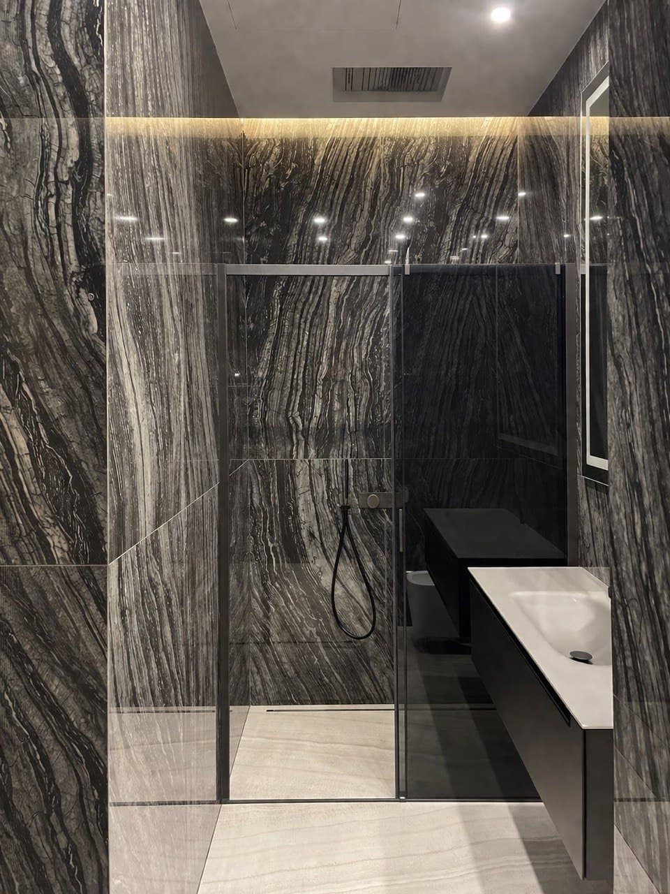 Shower room with dramatic stone slabs and a monolithic sink