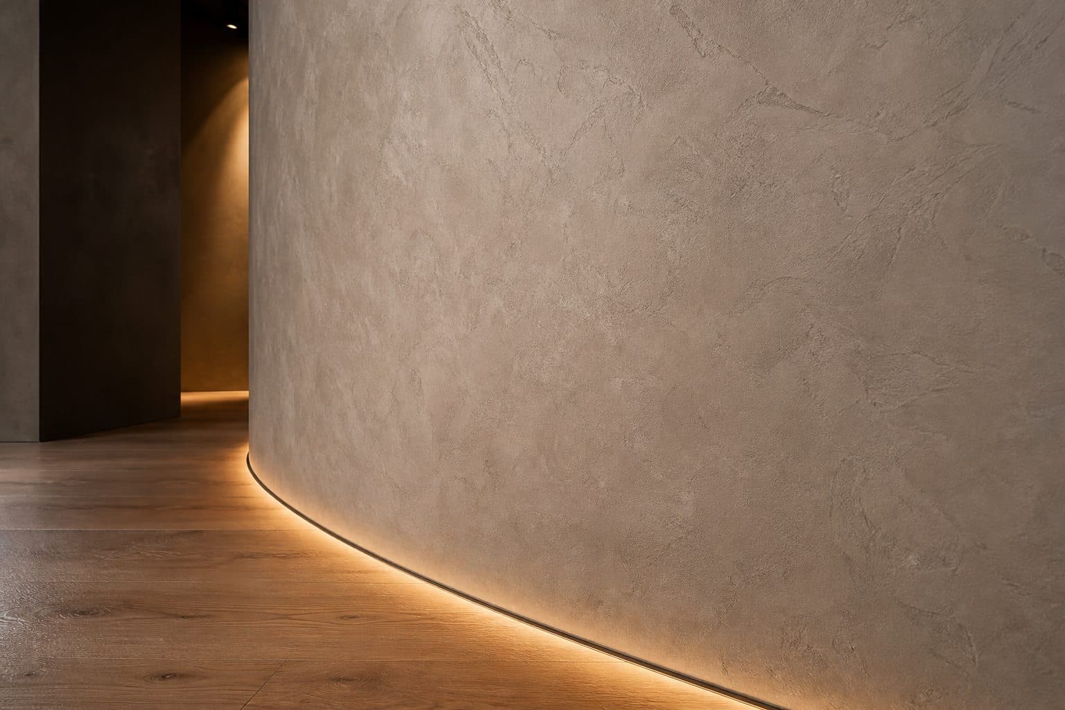 Pared curva con textura mineral gris cálida por capas bajo luz rasante