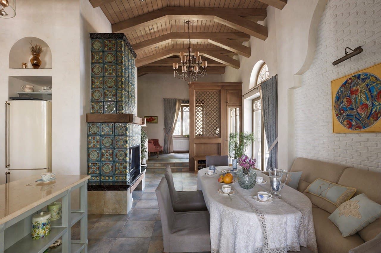 Open-plan living room with decorative plaster, tiled stove, and exposed beams