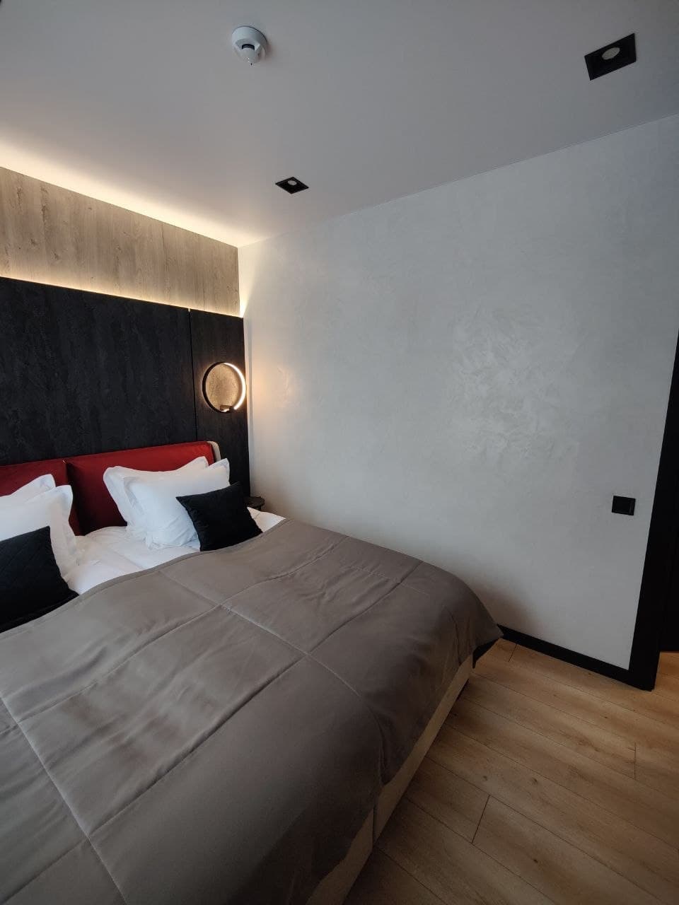 Bedroom with a matte decorative wall finish and integrated headboard lighting