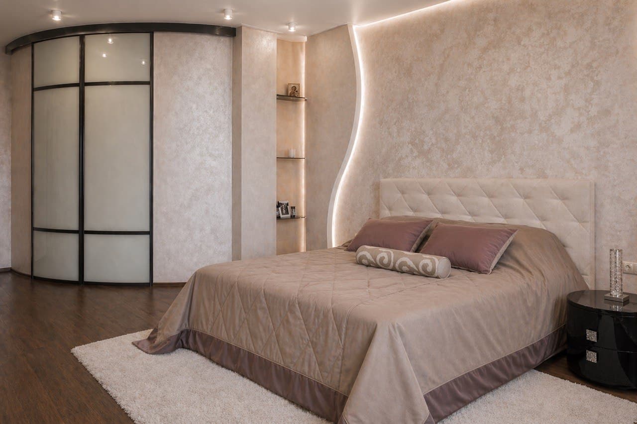 Bedroom with a curved wall composition, built-in wardrobe, and upholstered headboard