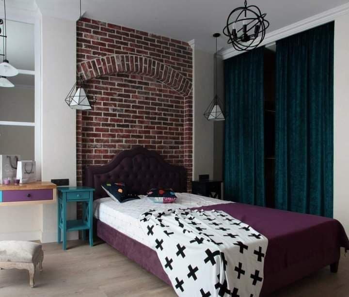 Bedroom with an exposed brick wall, decorative plaster, and jewel-tone textiles