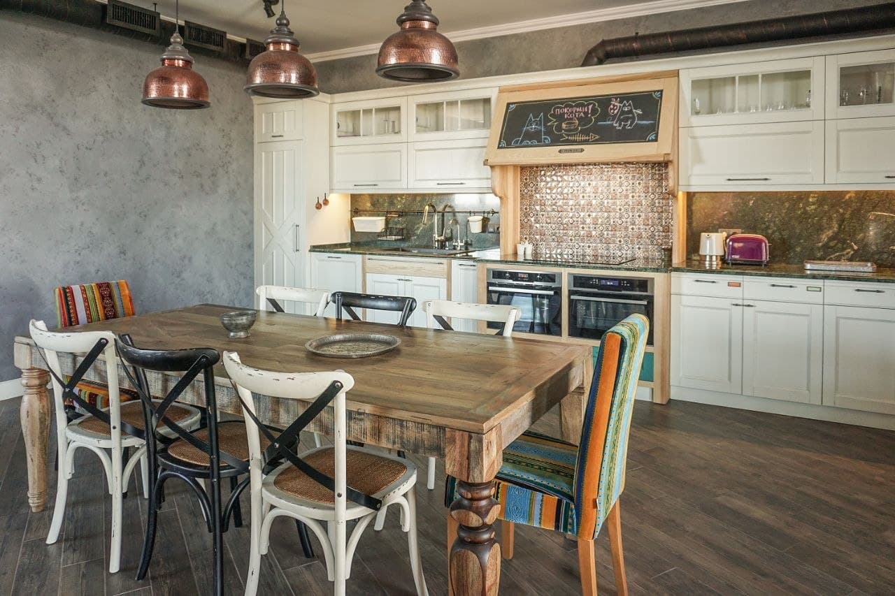 Kitchen and dining room with lime-effect walls, a rustic wood table, and copper pendants