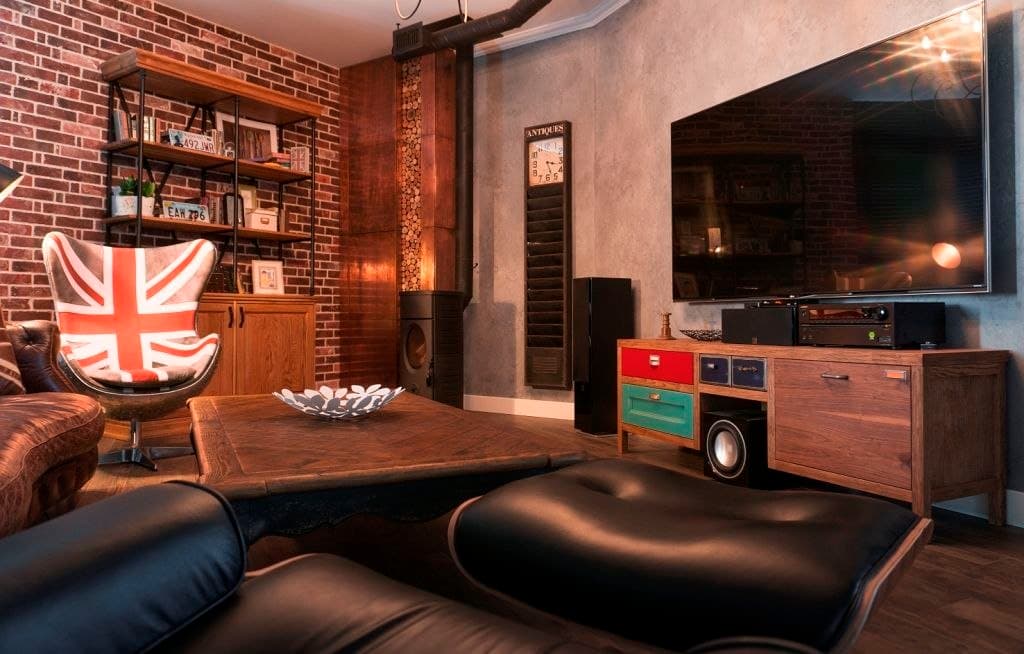 Media lounge with exposed brick, a leather sofa, and industrial shelving