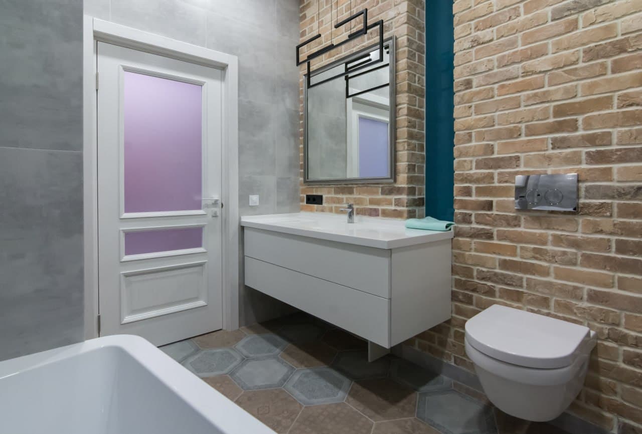 Bathroom with an exposed brick wall, floating vanity, and an integrated mirror