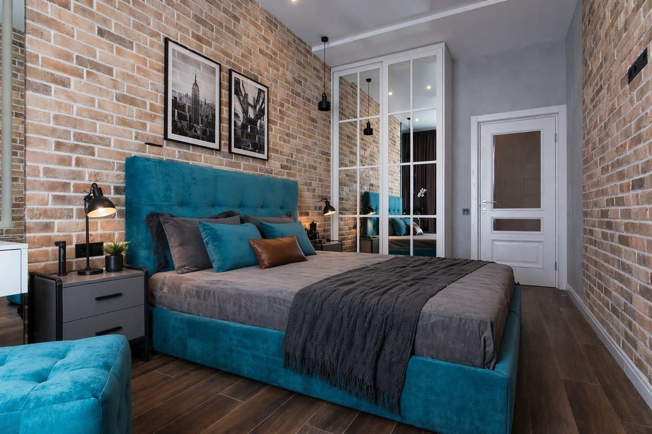 Bedroom with a brick feature wall, upholstered bed, and a glass partition