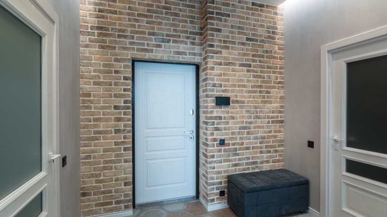 Entrance hall with brick cladding, clean white doors, and a tiled floor