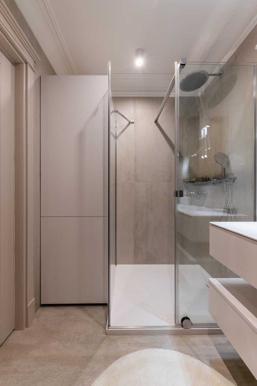 Bathroom corridor with a stone vanity, warm lighting, and concealed cabinetry
