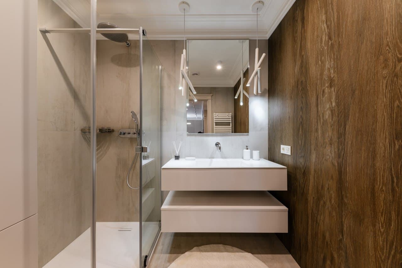 Bathroom with a wood veneer wall, floating vanity, and a glass shower