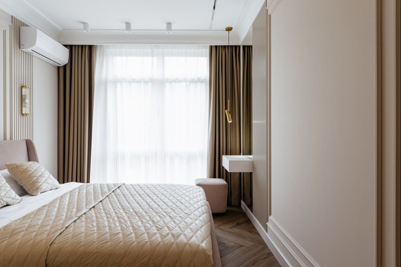 Bedroom with a full-height window, decorative trim, and a warm wood floor