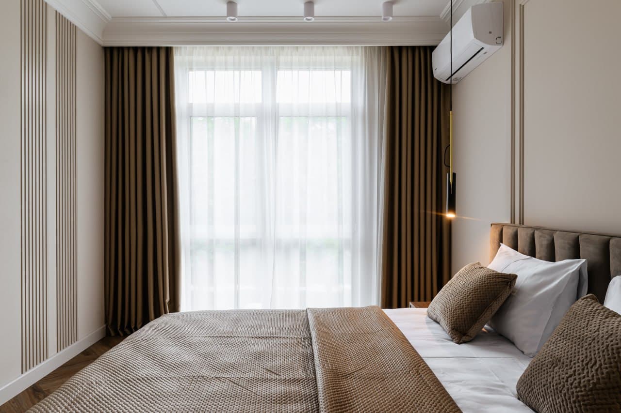 Bedroom with a full-height window, fluted walls, and tailored drapery