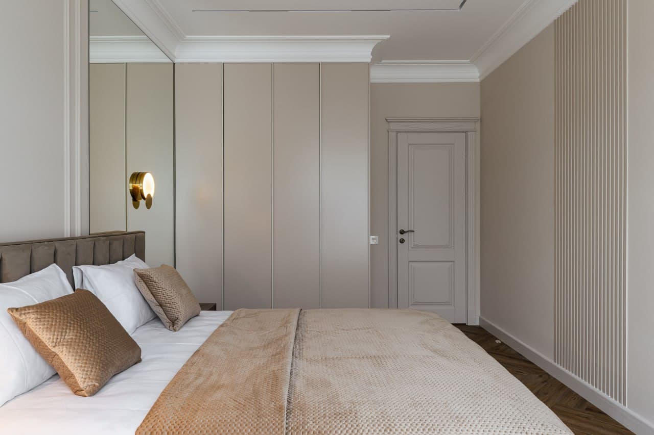 Bedroom with full wall paneling, classic trim, and concealed storage