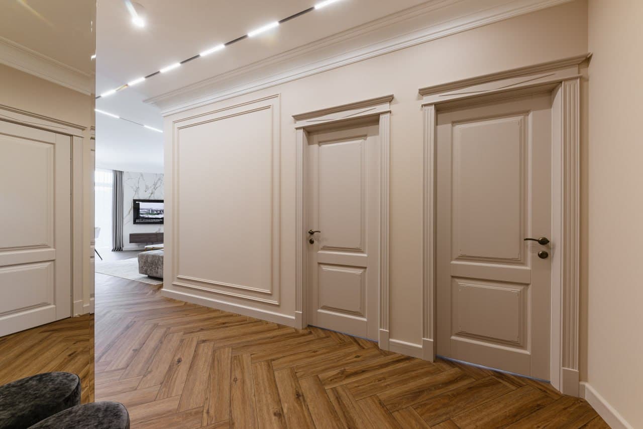 Corridor with paneled walls, precise moldings, and a herringbone floor