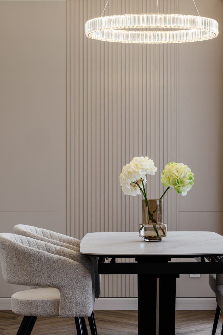 Dining table vignette with a ring chandelier and a fluted wall panel