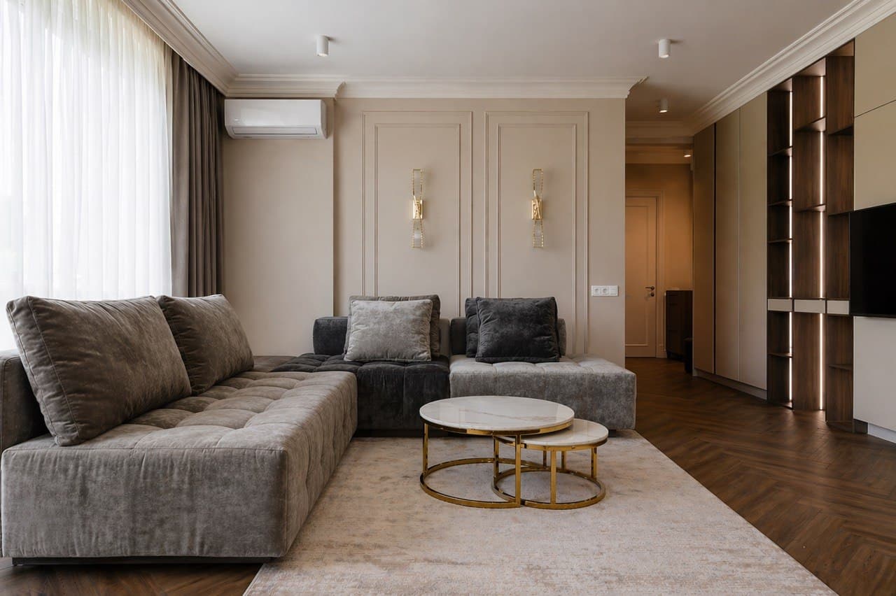 Living room with paneled walls, a beige decorative finish, and sculptural coffee tables
