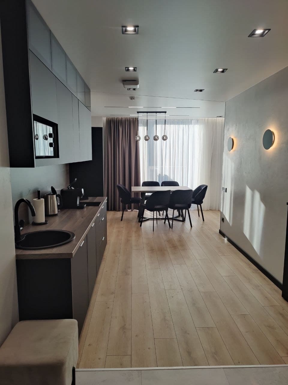 Galley kitchen and dining area with smooth decorative paint and a light wood floor