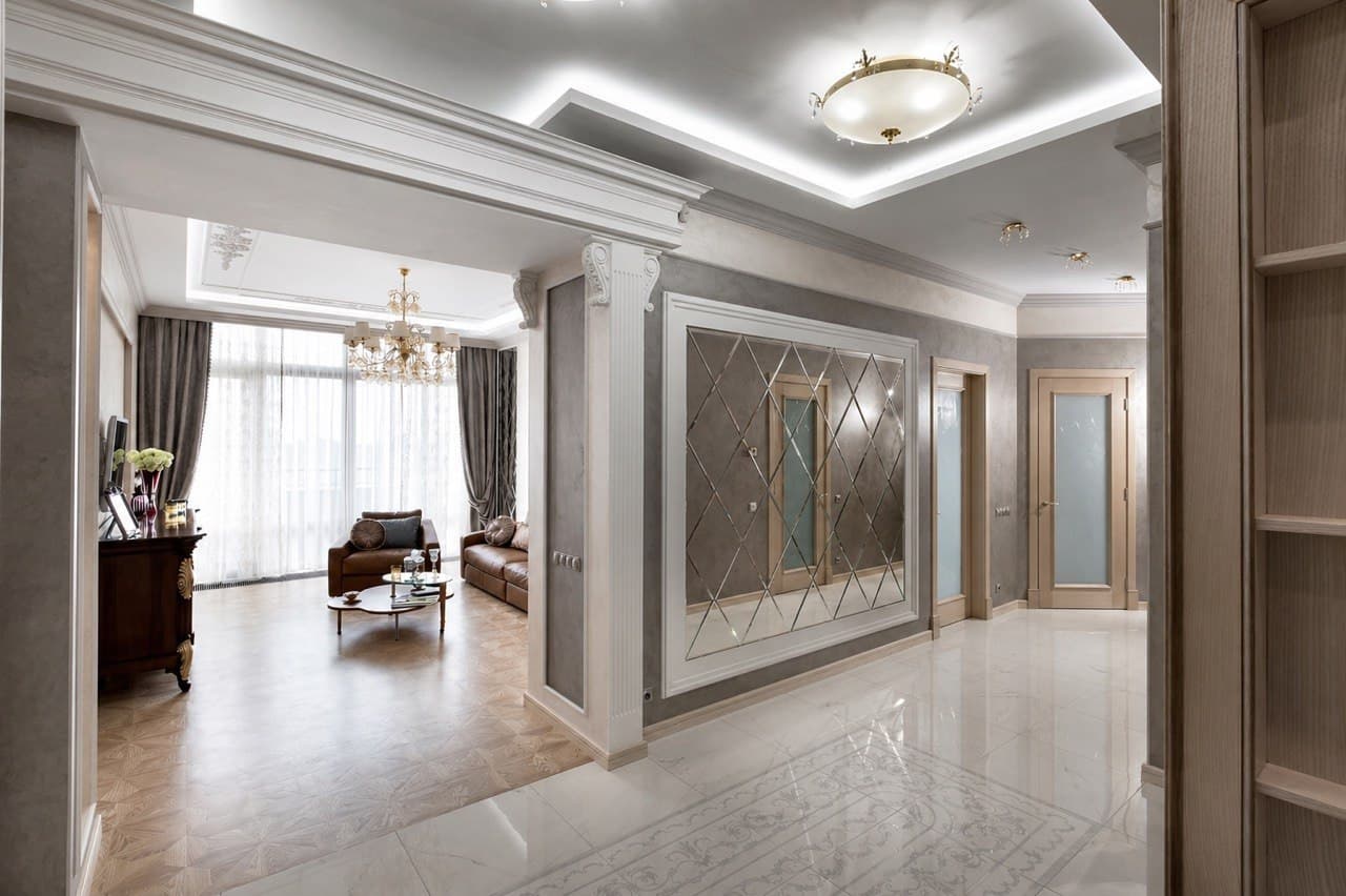 Hall with a reflective wall panel, decorative moldings, and a marble floor