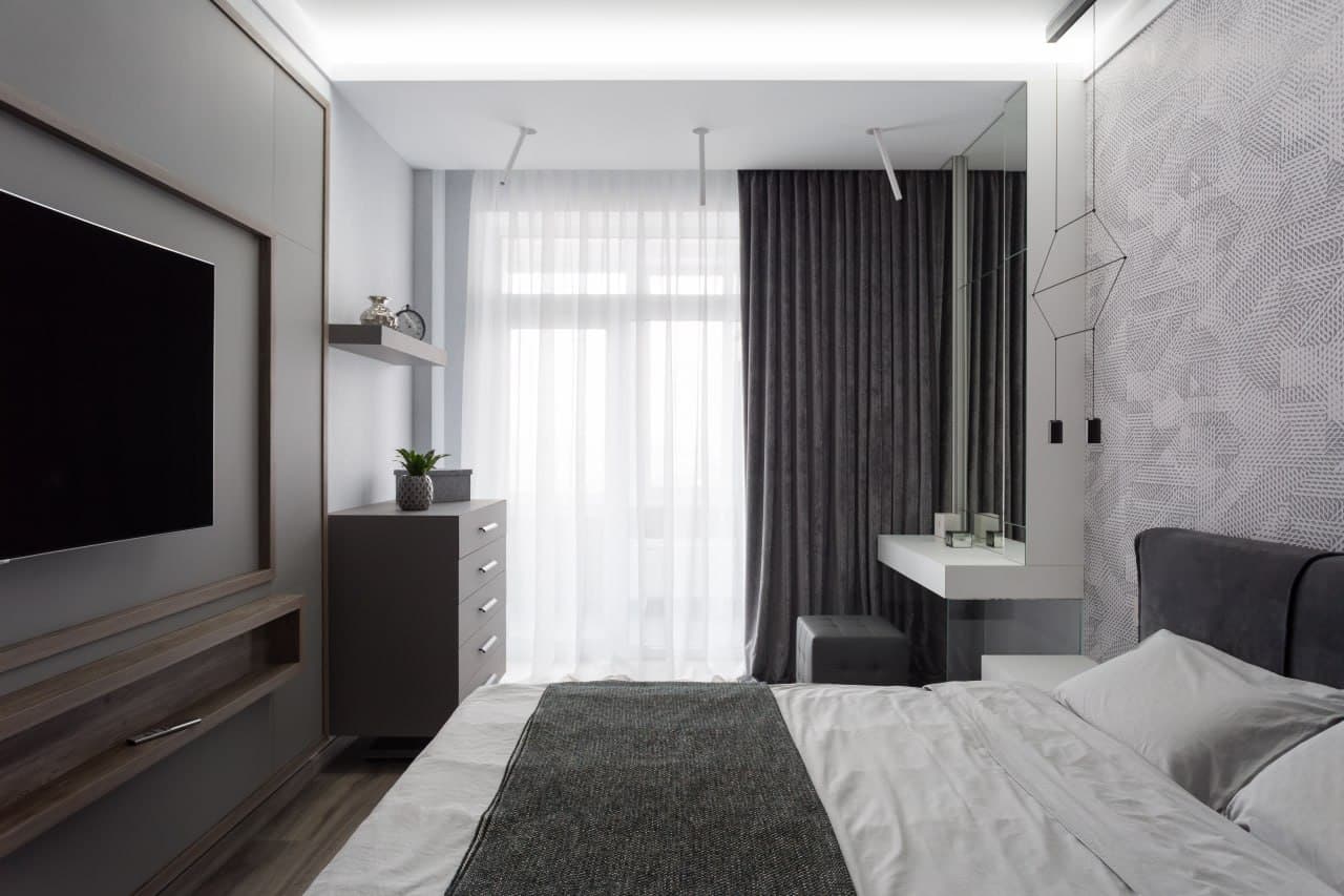 Bedroom with a decorative plaster wall, mirror panel, and integrated desk