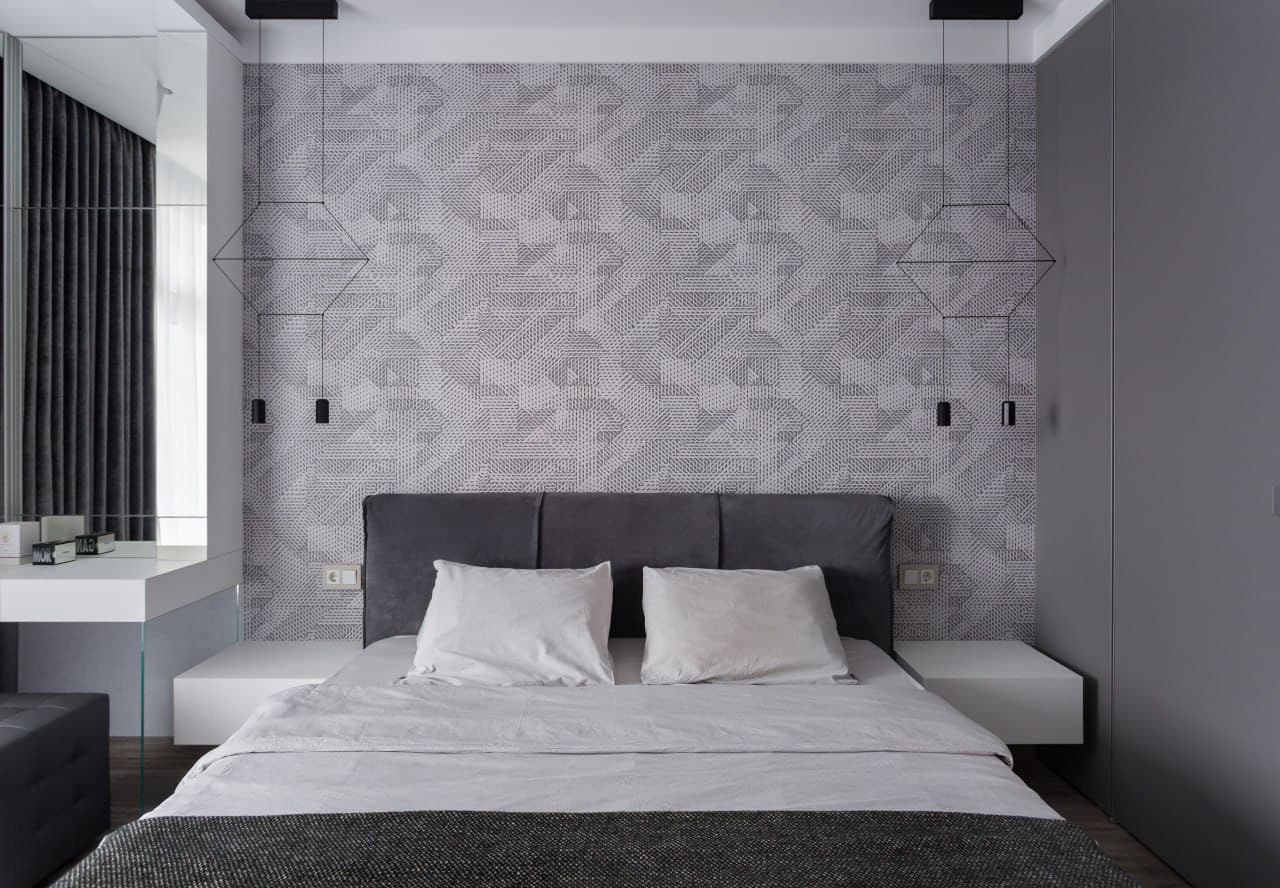 Bedroom with a textured accent wall, mirror panel, and a soft grey palette