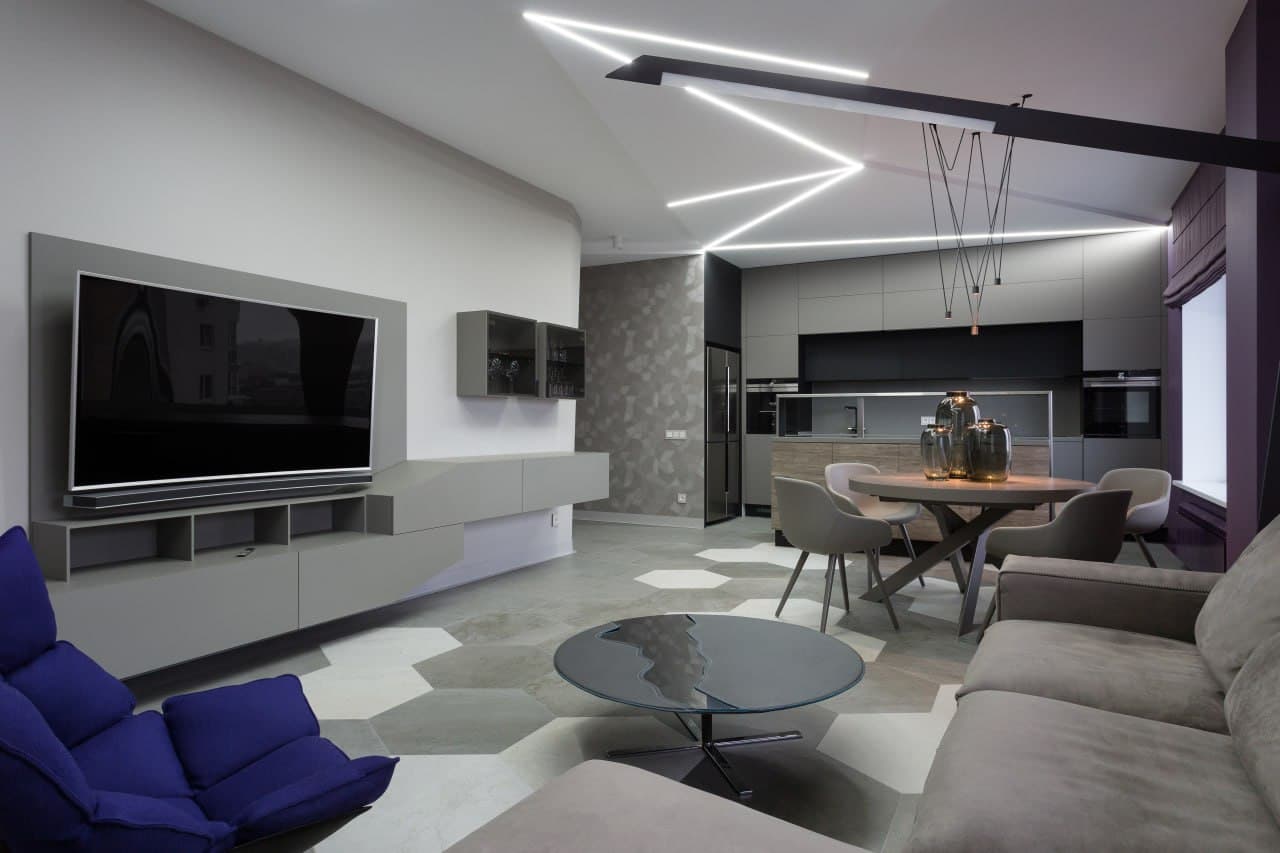Living room with a textured wall finish, linear ceiling geometry, and an open kitchen