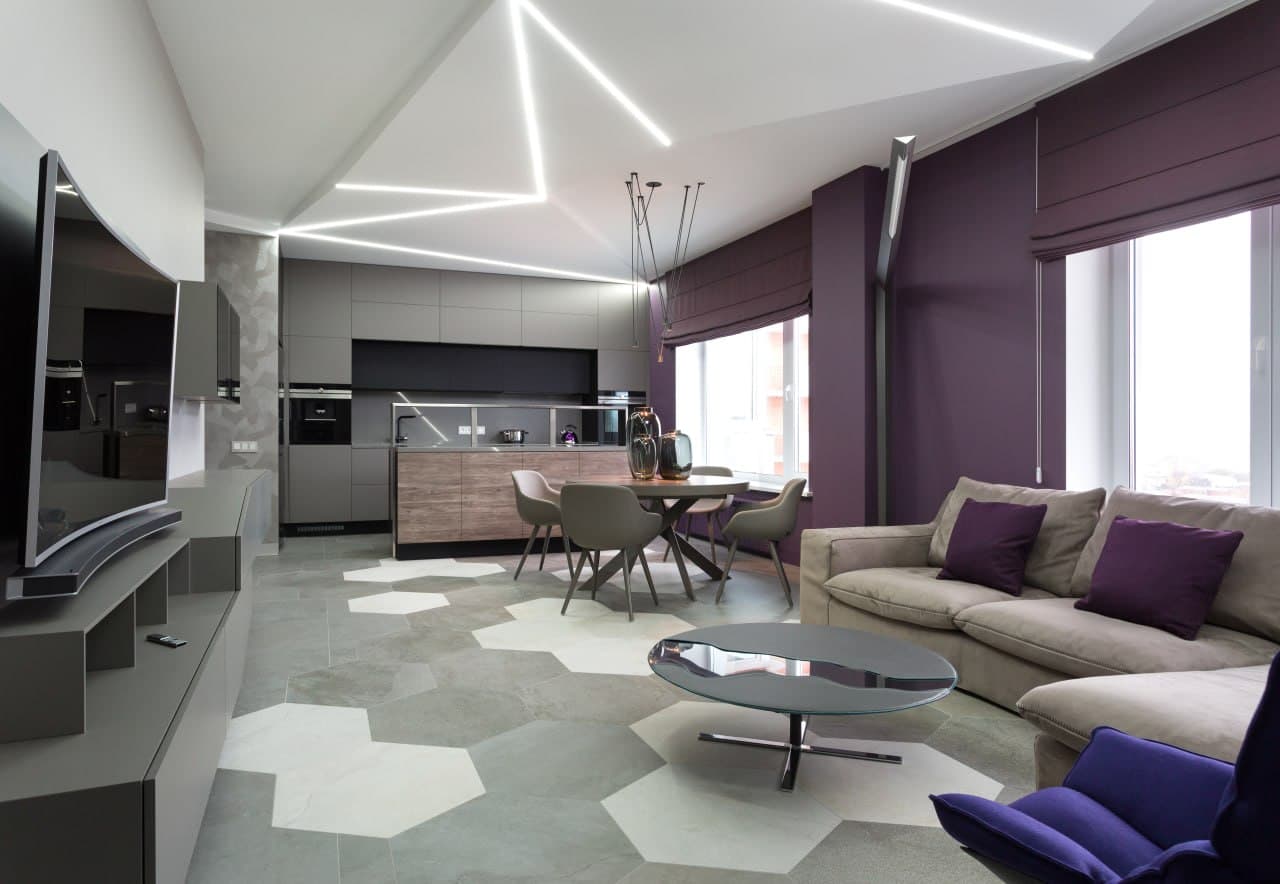 Open-plan living room with gradient decorative paint, angular ceiling lighting, and violet accents