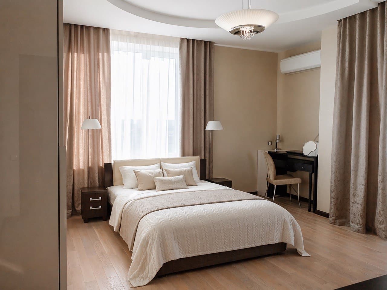 Bedroom suite with layered curtains, smooth decorative paint, and a work nook