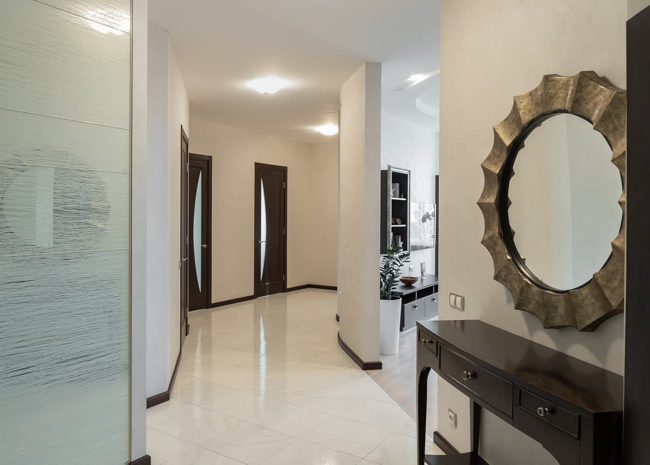 Hallway with a minimalist wall composition, large mirror, and seamless transitions