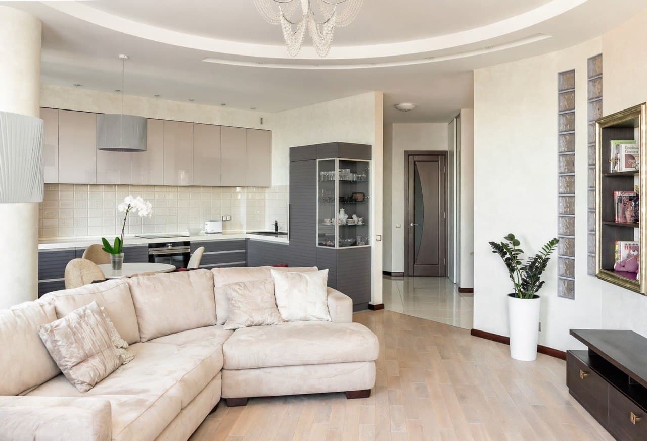 Open-plan living room and kitchen with soft matte finishes and a curved ceiling