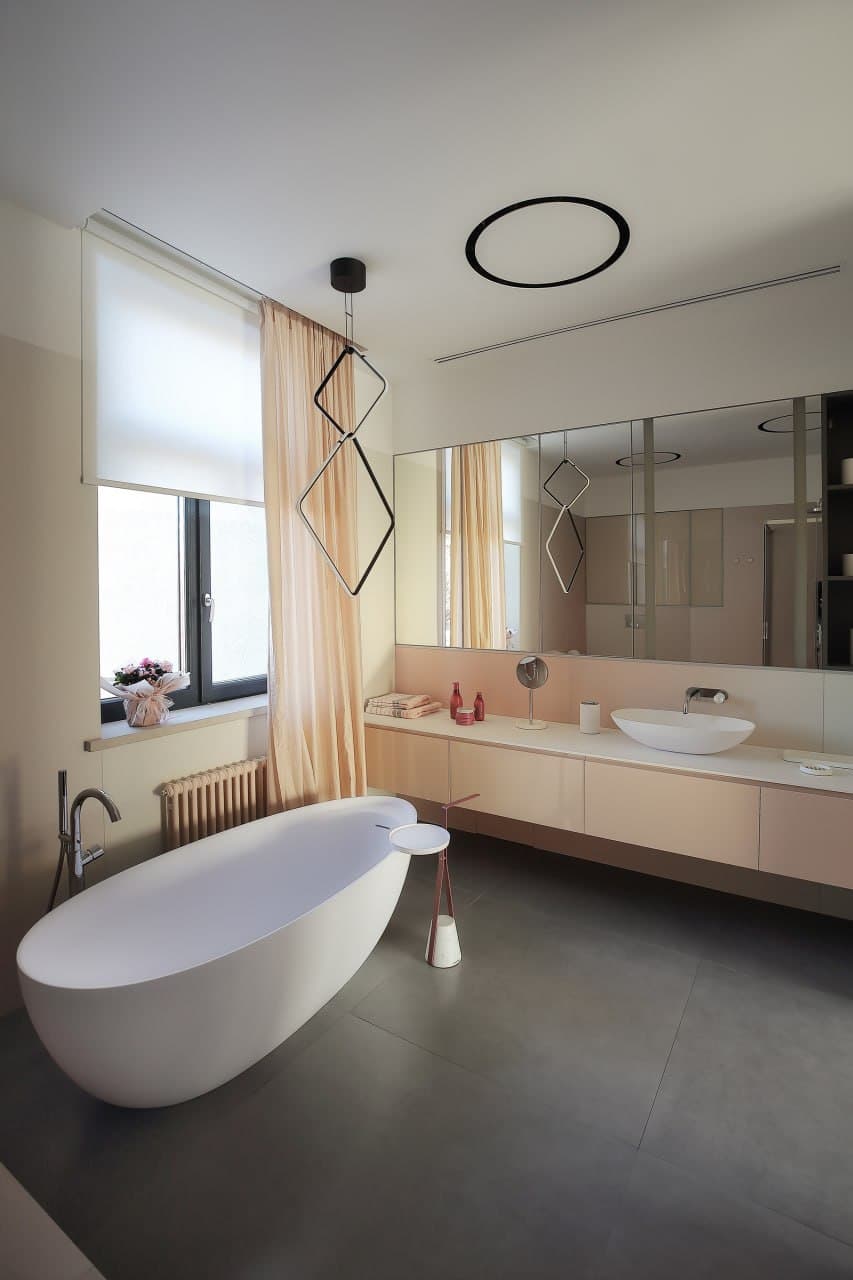 Spa bathroom with a microcement floor, freestanding tub, and blush vanity