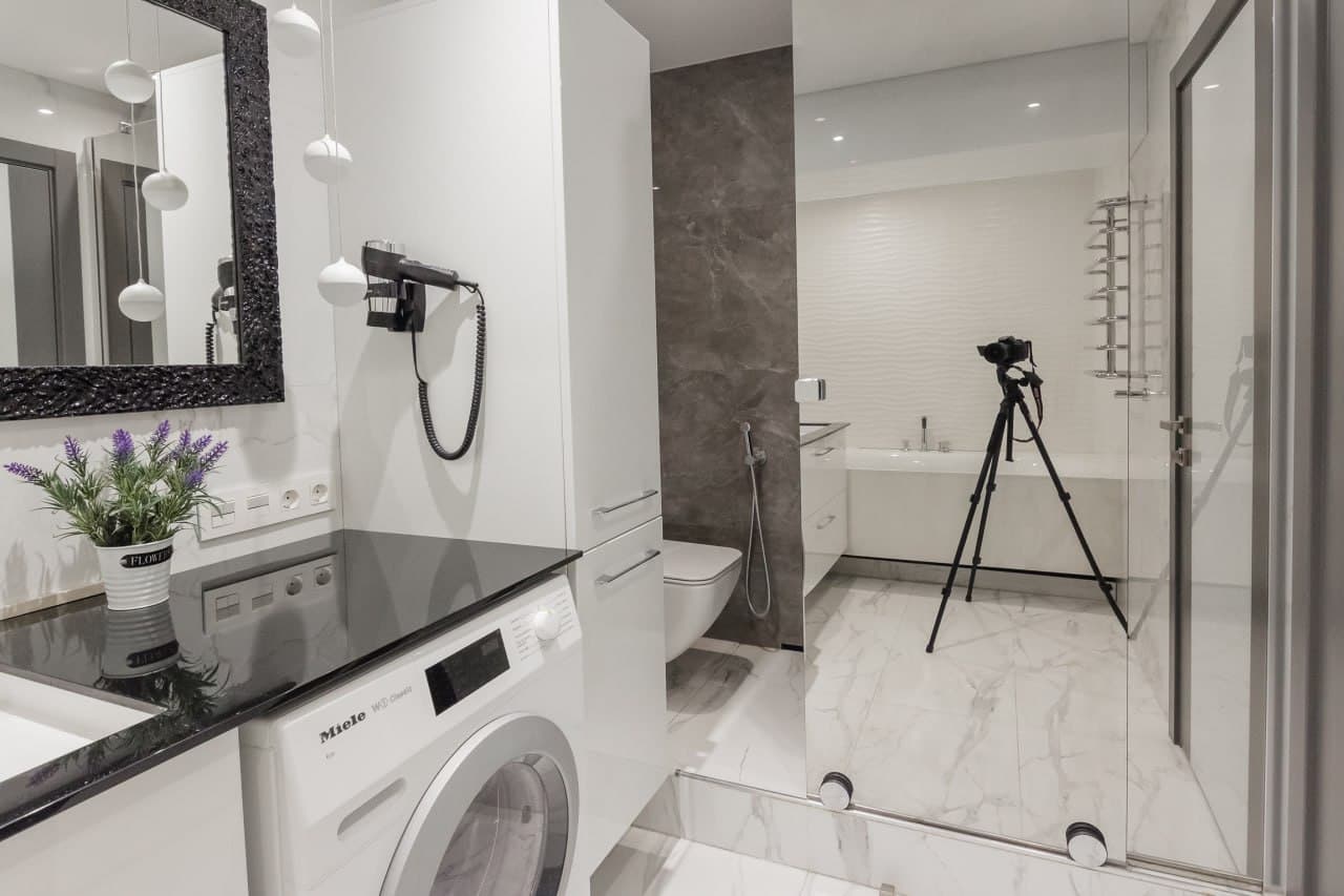 Bathroom with a large mirror, walk-in shower, and a marble-look finish