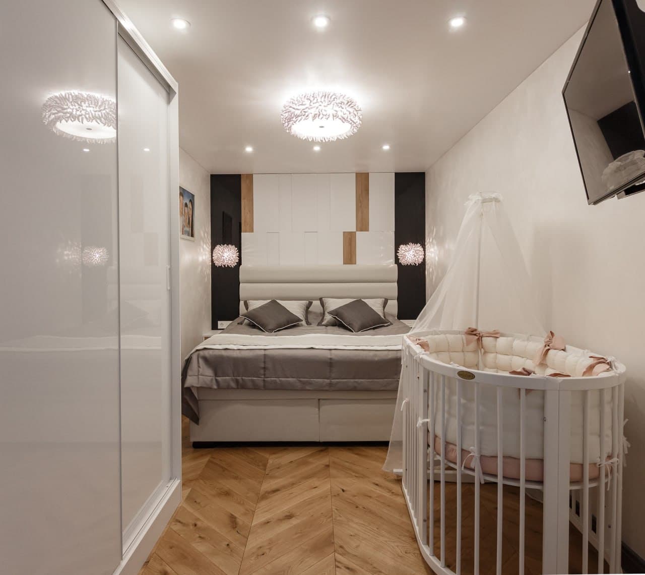 Bedroom entrance with a warm decorative finish, crib, and herringbone floor