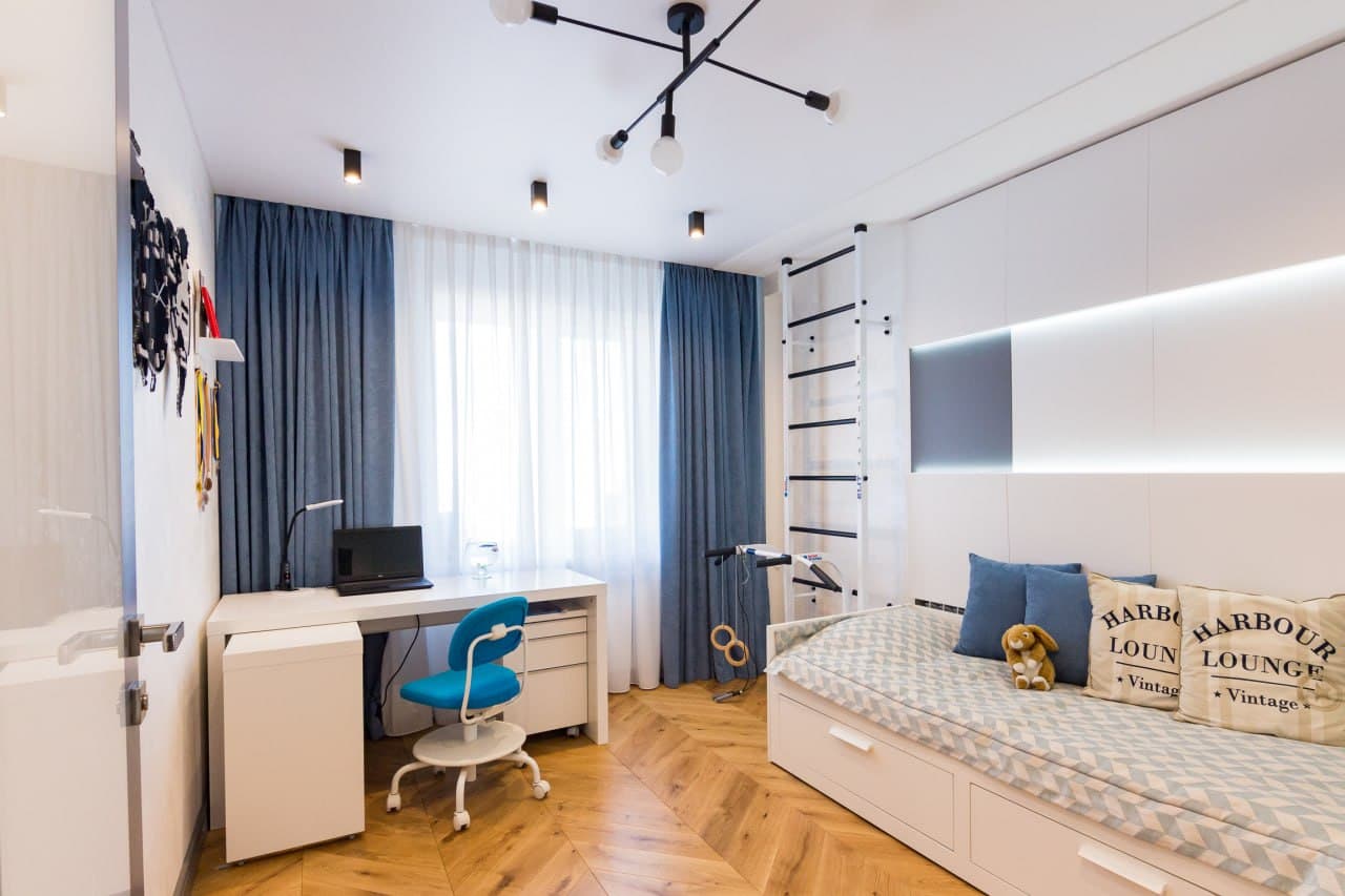 Children's room with a decorative paint wall, study desk, and blue drapery