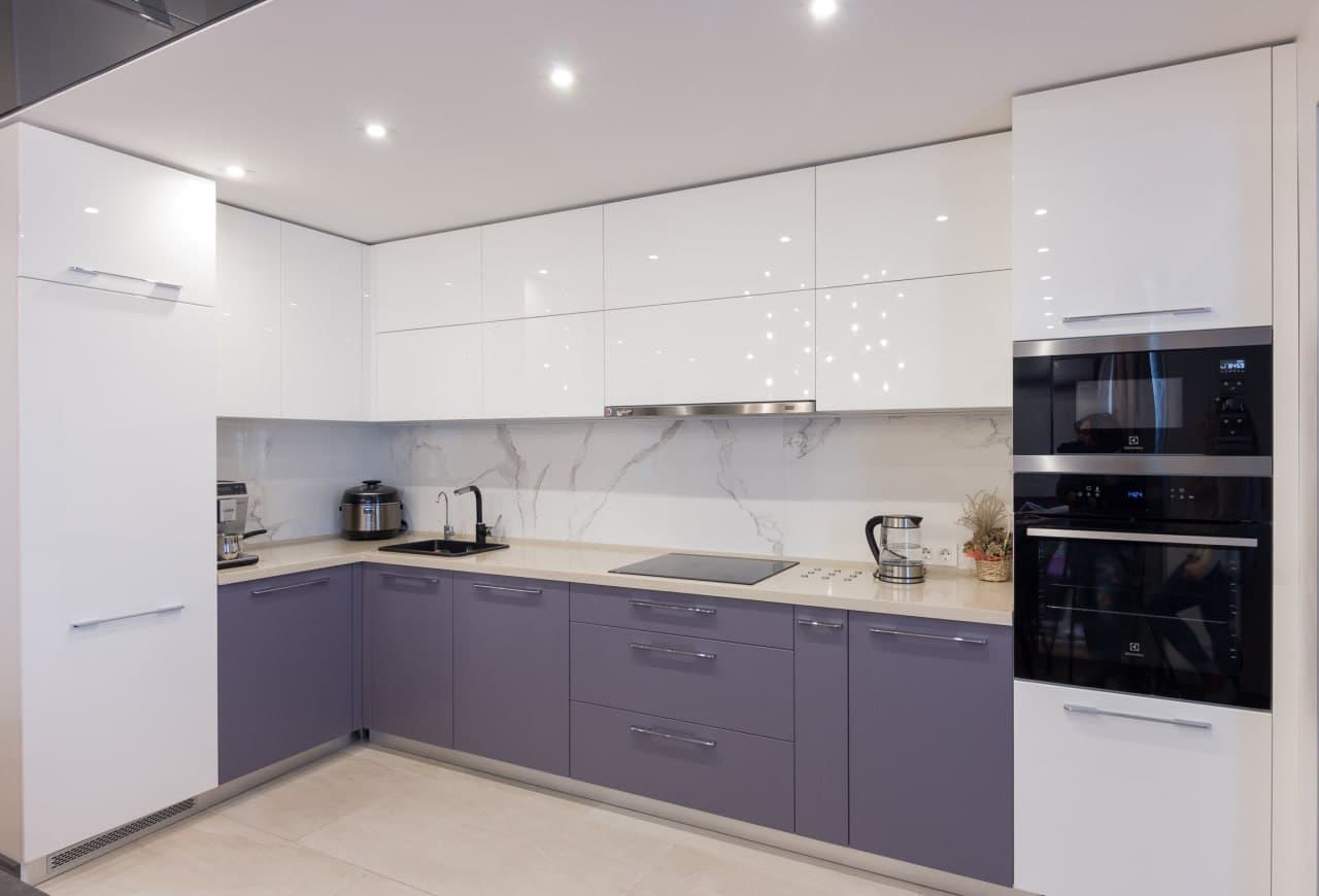 Compact kitchen with glossy cabinetry, pale lilac base units, and a clean backsplash