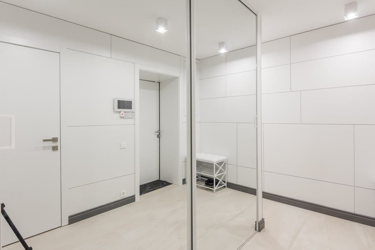 Hallway with flush wall panels, mirrored wardrobe, and minimalist geometry