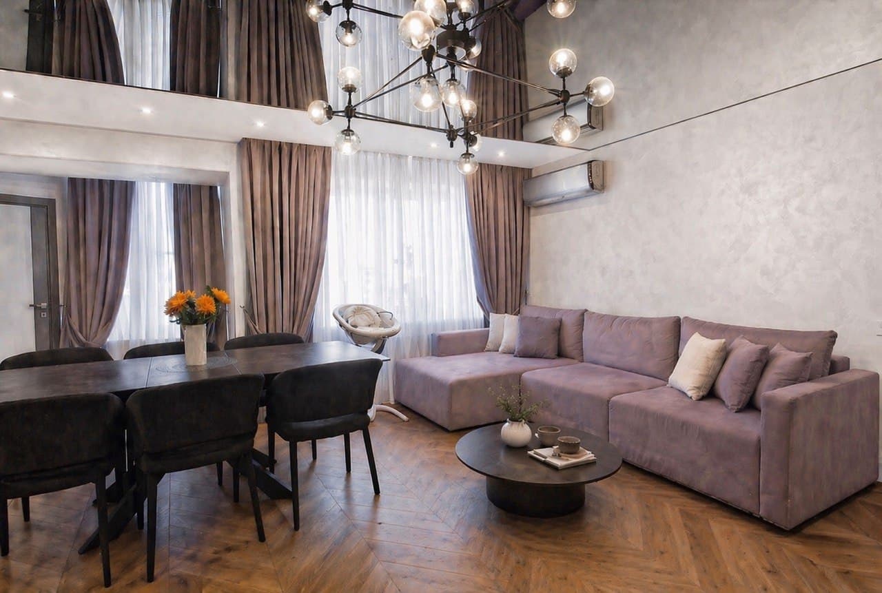 Lounge corner with chandelier, decorative plaster wall, and layered curtains