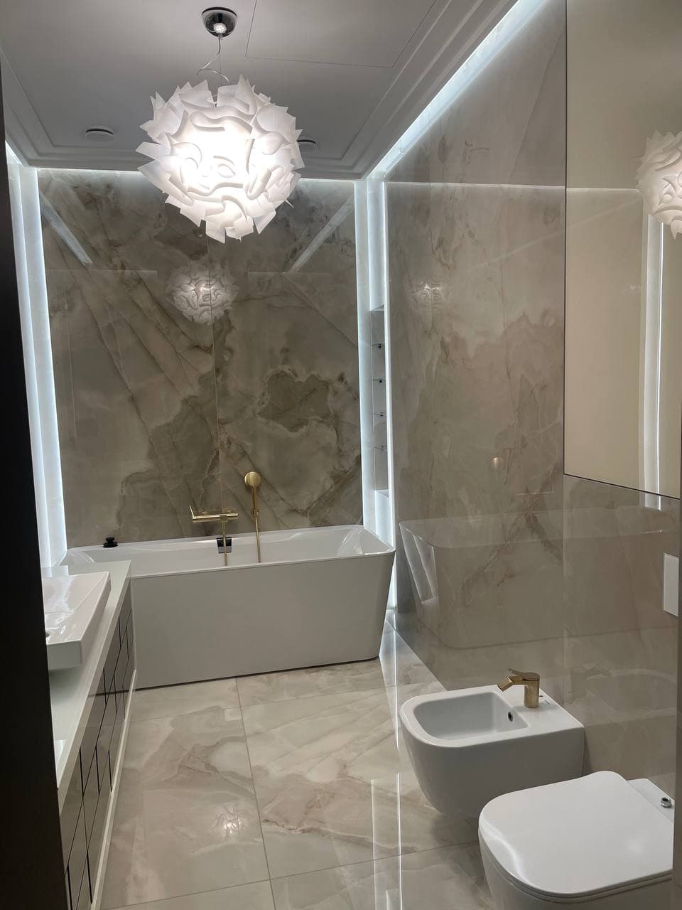 Bathroom with stone walls, glass shower, and an integrated LED frame