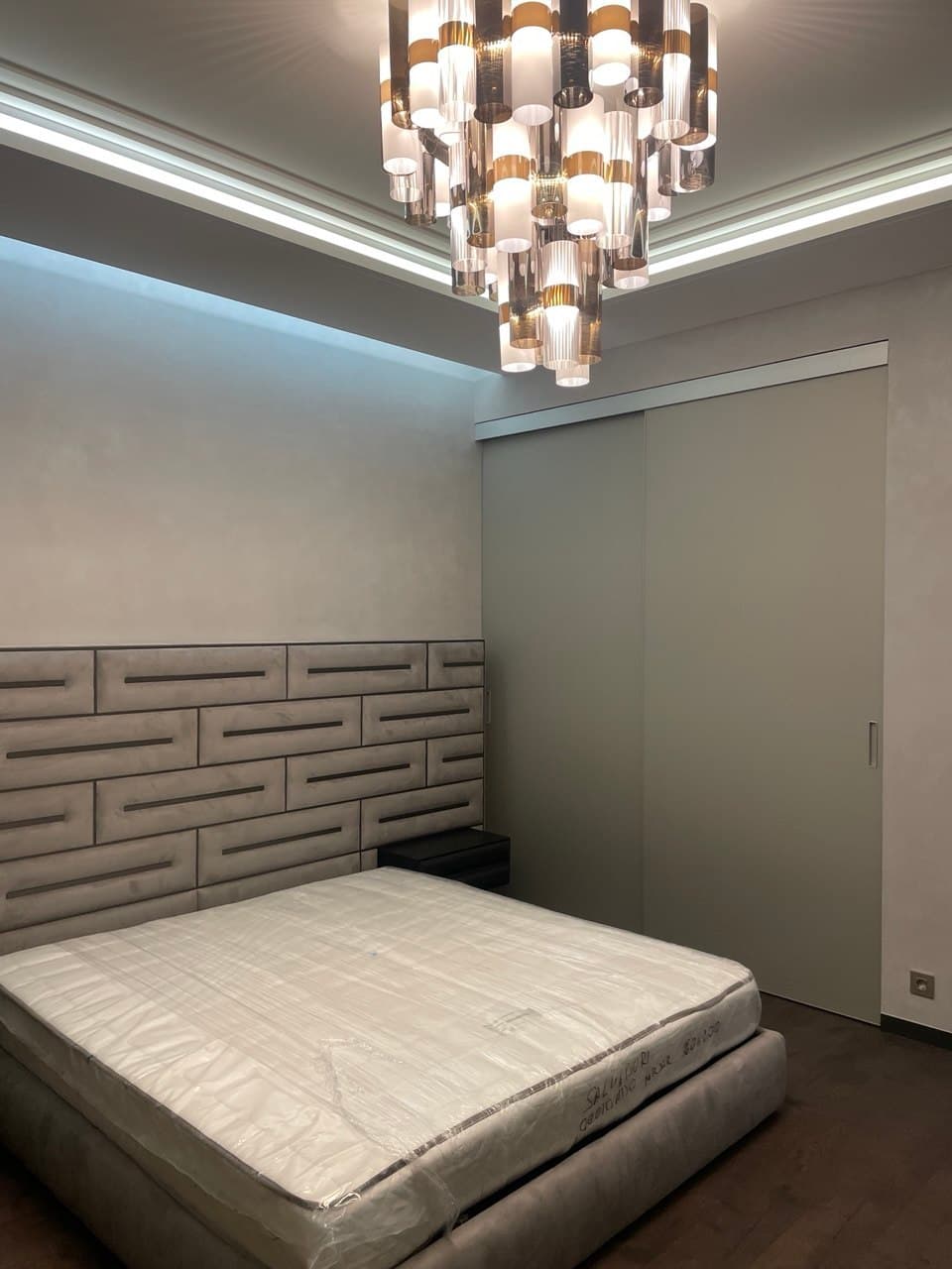 Bedroom corner with a textured wall finish and a statement chandelier