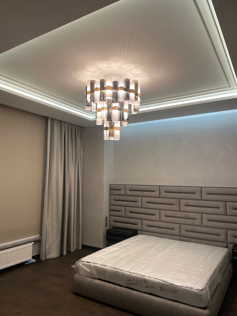 Bedroom with a geometric upholstered headboard and cove lighting