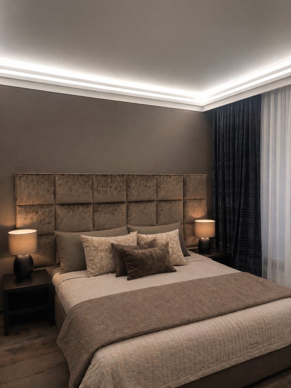 Bedroom with an upholstered headboard, warm taupe palette, and hidden lighting
