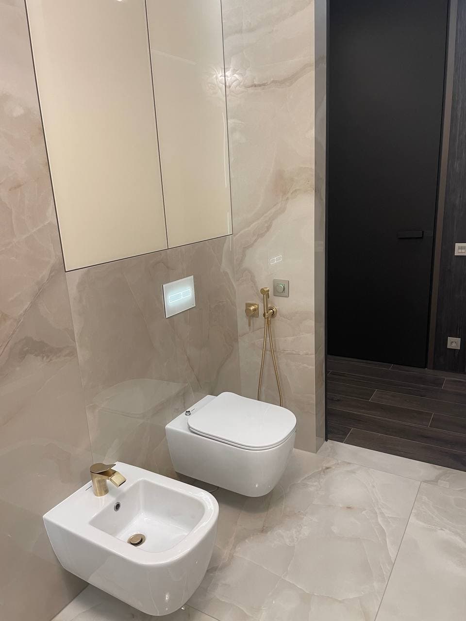 Guest bathroom with a soft stone finish, wall-hung sanitaryware, and warm lighting