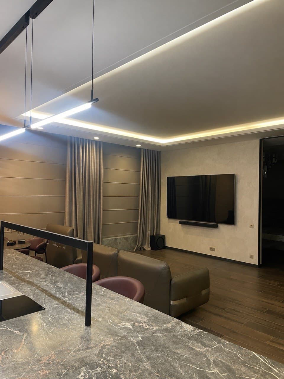 Living room with a stone island, floating media wall, and shadow-gap ceiling