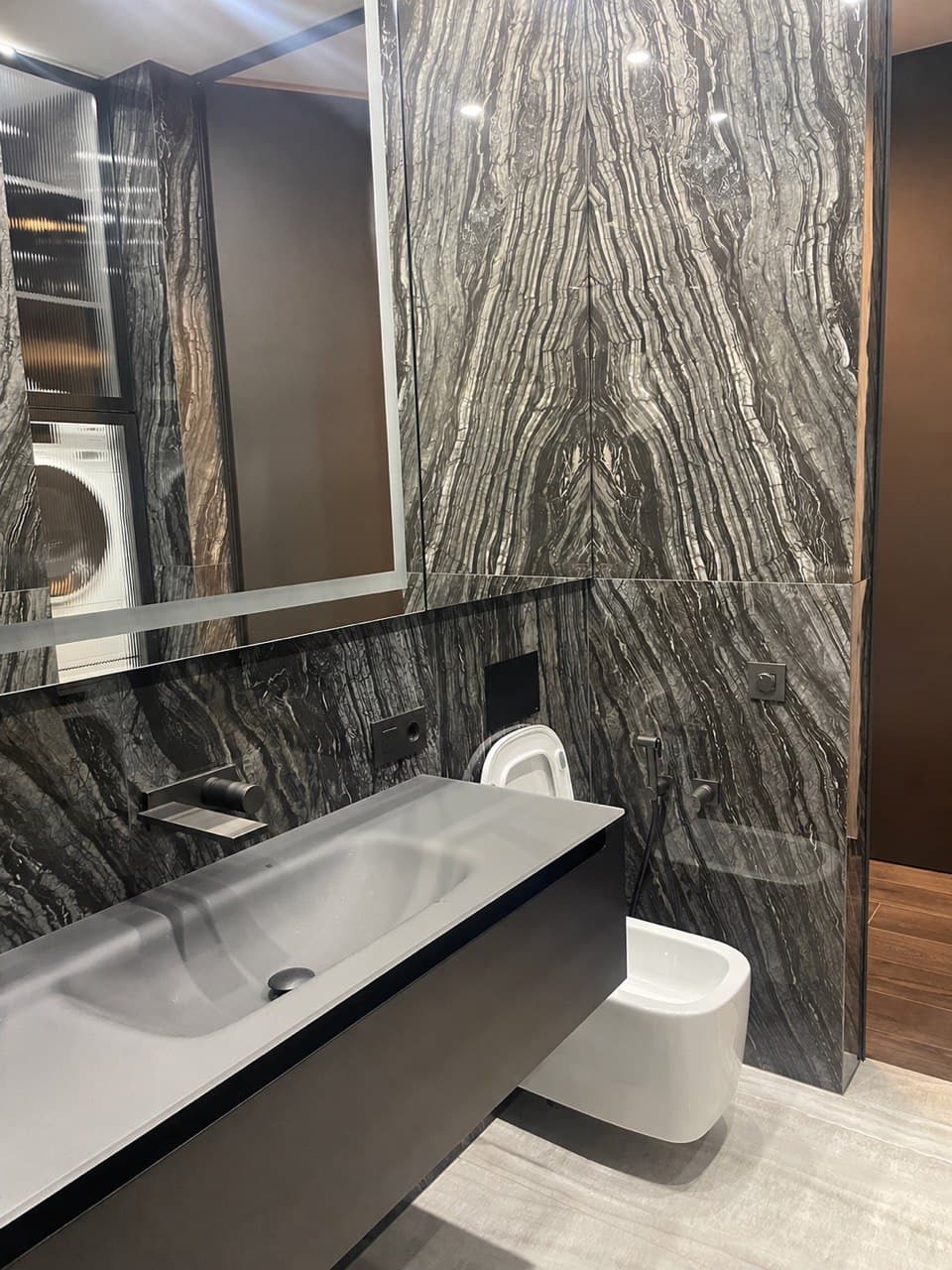 Powder room with a book-matched stone wall, floating vanity, and a mirrored cabinet