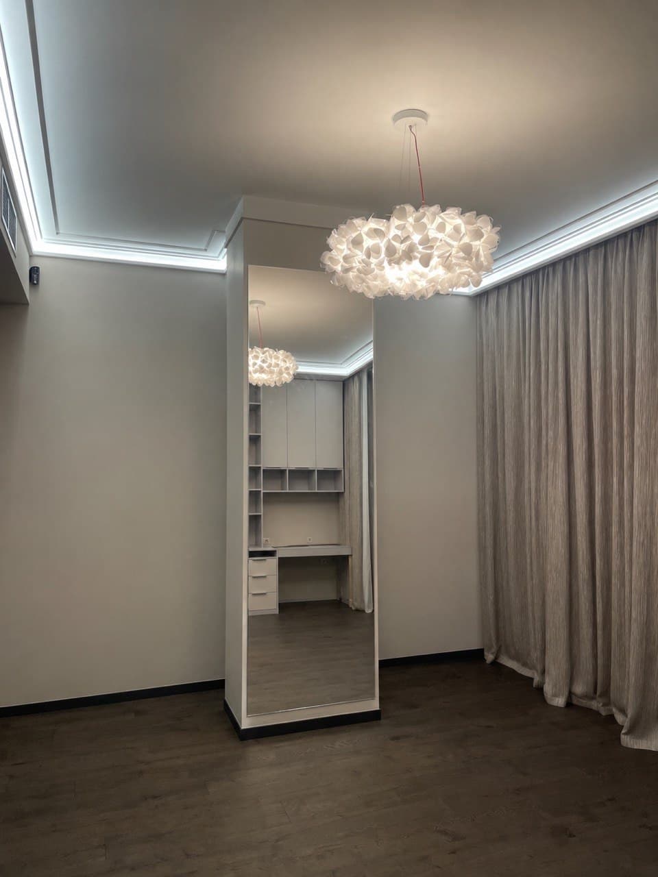 Walk-in wardrobe with soft matte walls and a sculptural pendant