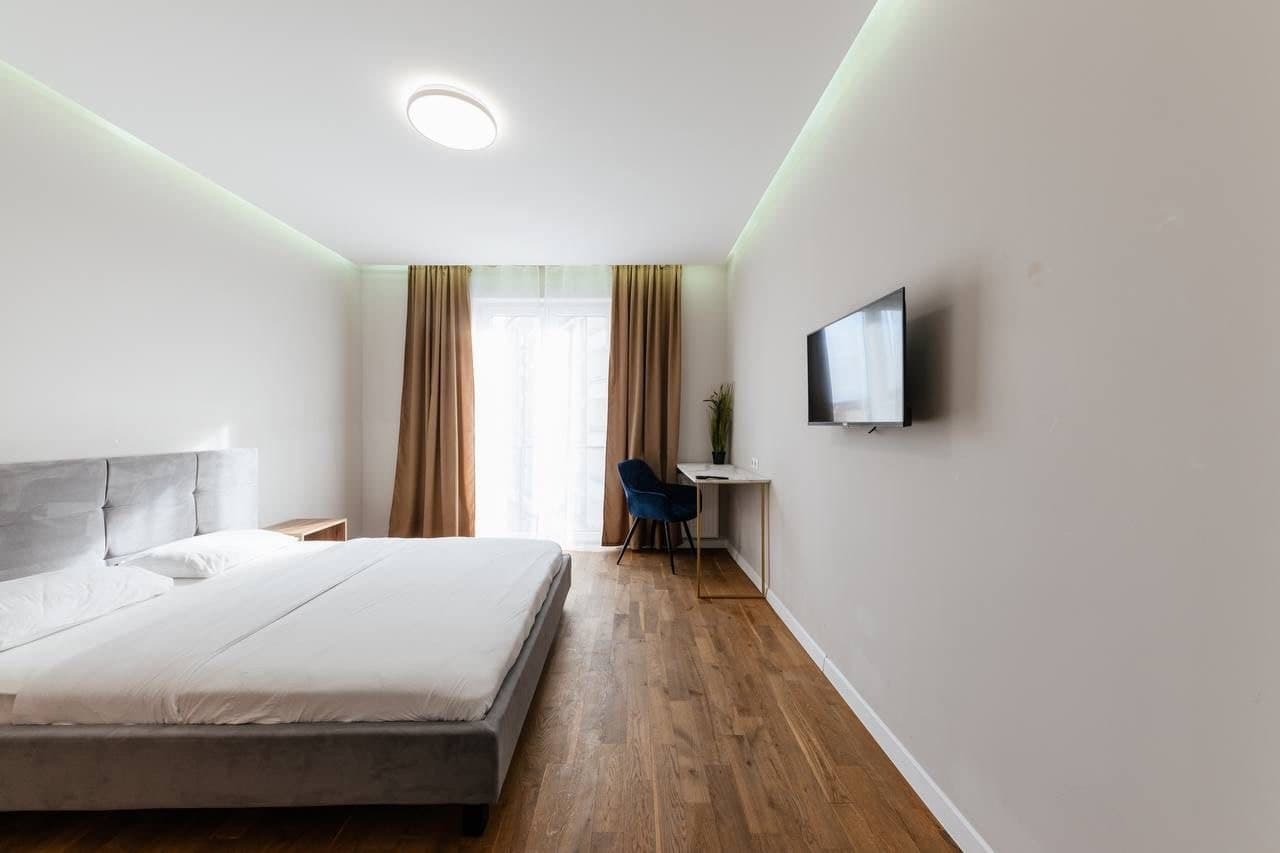 Minimalist bedroom with a wall TV, linear lighting, and a long perspective